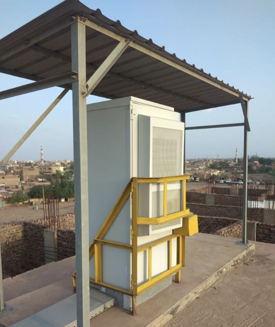 Outdoor telecom cabinet under a shade canopy on a rooftop